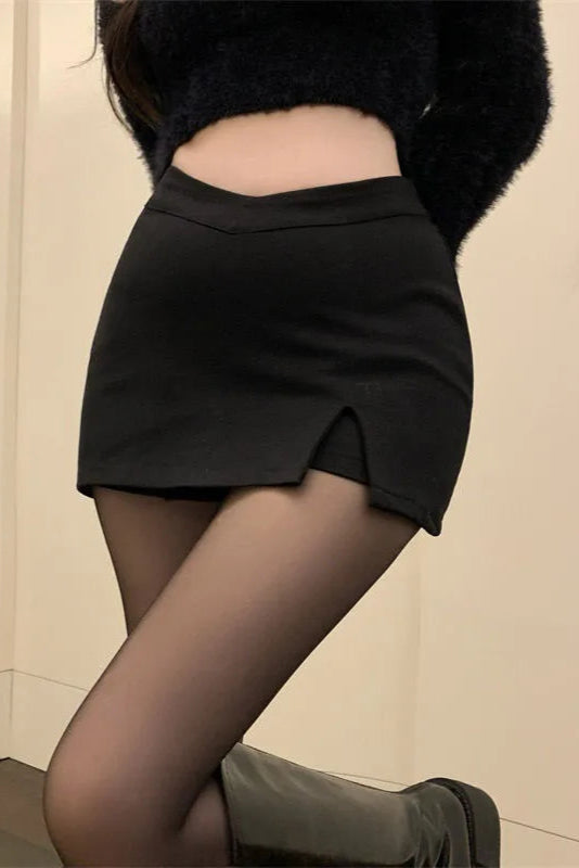 Person wearing a black skirt and black top against a beige wall.