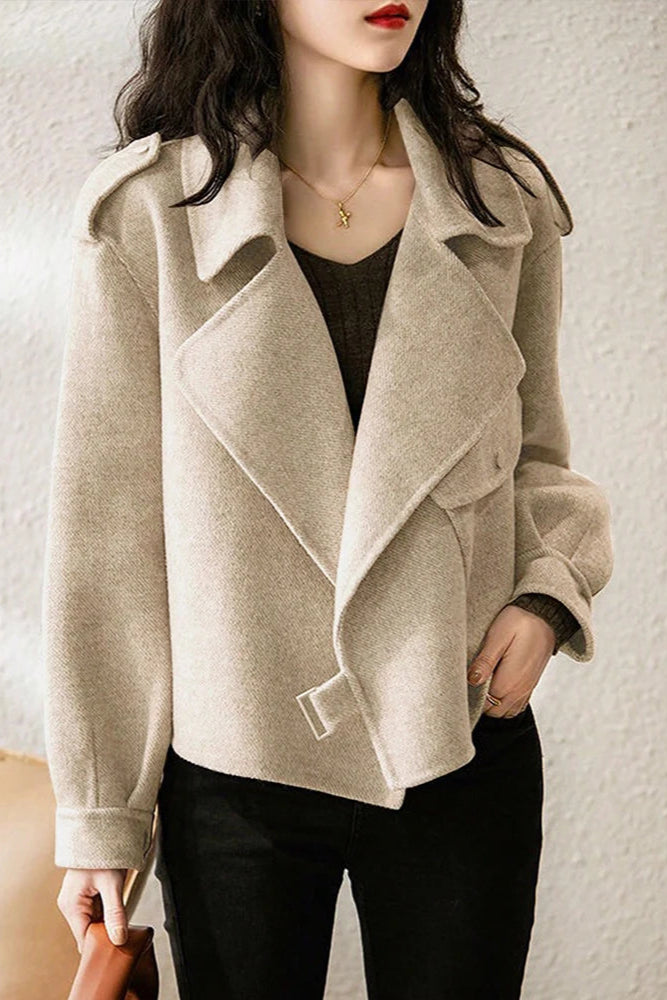 Beige coat worn by a person against a neutral background