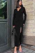 Woman in a black dress standing against a stone wall.