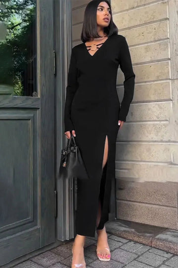 Woman in a black dress standing against a stone wall.